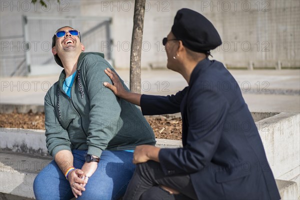 Gay Latino male couple sitting on a bench in a park