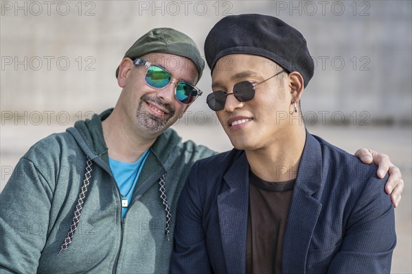 Gay Latino male couple sitting on a bench in a park