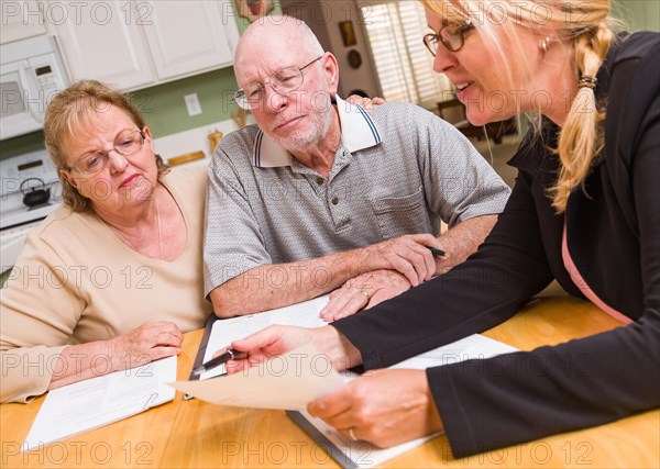 Senior adult couple going over documents in their home with agent at signing