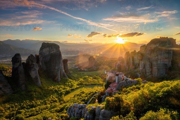 Sunset over monastery of Rousanou and Monastery of St. Nicholas Anapavsa in famous greek tourist destination Meteora in Greece on sunset with sun rays and lens flare