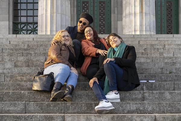 Multi ethnic group of friends sitting on some stairs having a good time chatting and laughing