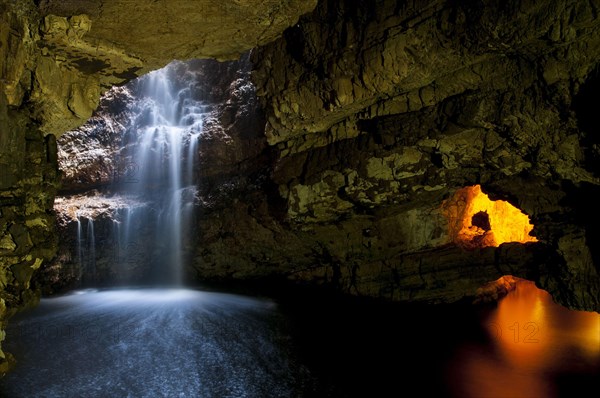 Waterfall flowing through sinkhole into cave