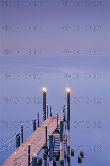 Rosa-violette Abendstimmung ueber dem Bodensee mit beleuchtetem Badesteg zum See