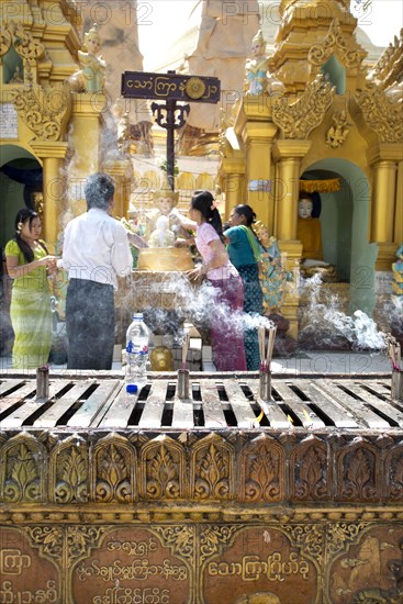 Smoke from burning incense with people at the Buddhist altar