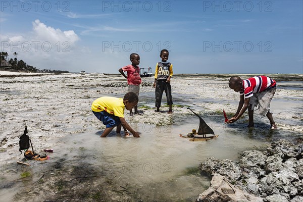 Kinder spielen im flachen Wasser mit selbst gebautem Boot