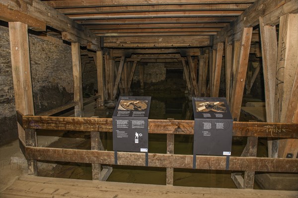 Tourist information board on the construction of an amphitheatre in the basement of the arena cellar of the historic Roman amphitheatre of Trier Treverorum Augusta with wooden supports in groundwater