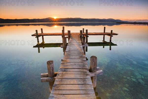 Holzsteg am Pfaeffikersee im Gegenlicht bei Sonnenaufgang mit Blick zum Bachtel und Glaernisch im Hintergrund