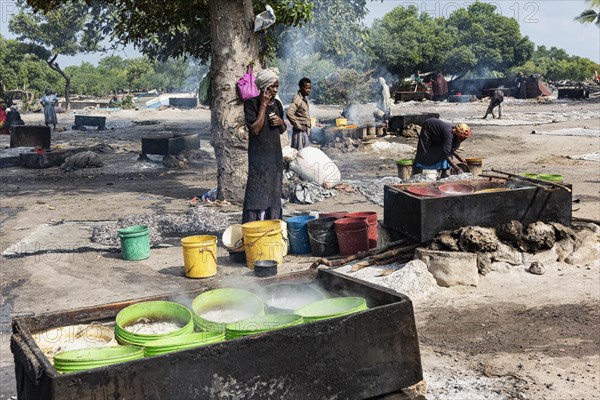 Frauen kochen Sardellen fuer Fischsauce ueber Feuerstellen