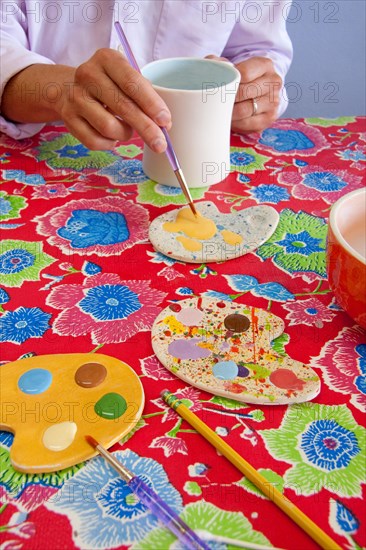 An adult male painting a coffee mug