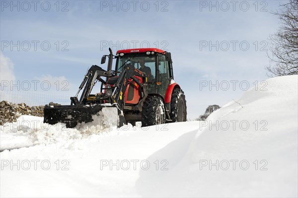 Zetor tractor with loader clears snow from blocked country road after snowstorm