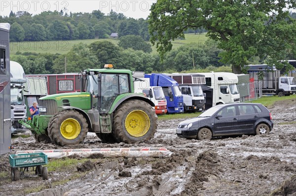 John Deere 6930 tractor pulls car from muddy car park at agricultural show cancelled due to bad weather