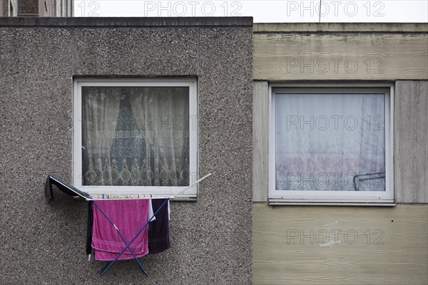 Laundry rack hanging out of the window on the first floor of a dreary apartment block