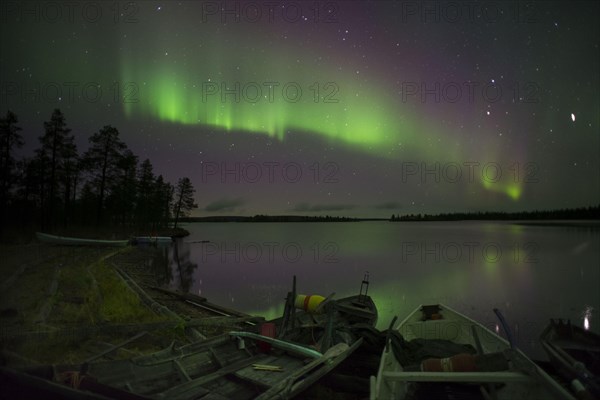 Aurora and stars over the lake with stranded canoes at night