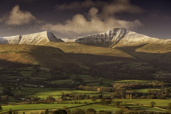 View of farmland and snow-capped hills at sunrise