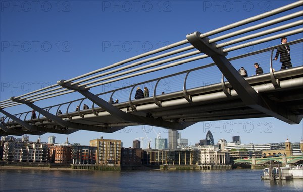 Pedestrians crossing river on steel suspension bridge