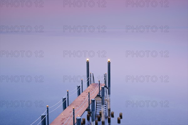 Rosa-violette Abendstimmung ueber dem Bodensee mit beleuchtetem Badesteg zum See