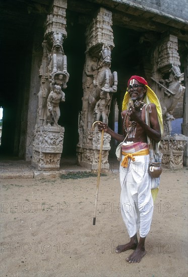 Vaishnavite devotee standing in front of Shesharayar Mandapam sculptures in Srirangam temple