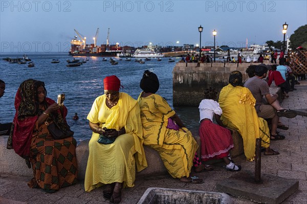 Frauen in bunten Tuechern sitzen an der Promenade des Fodharani Park