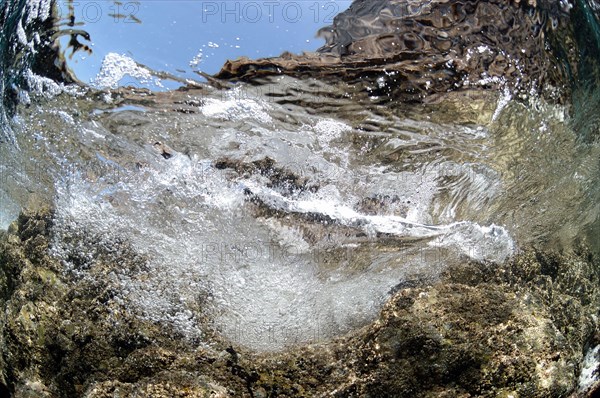 Wave breaking on rocky ledge underwater