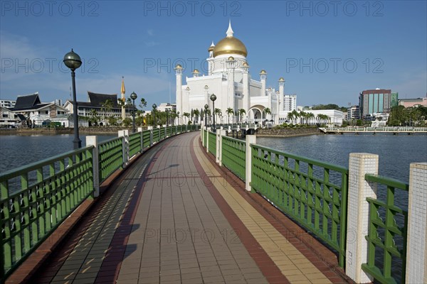 View of the walkway across the artificial lagoon to the mosque with gold dome and marble minerettes