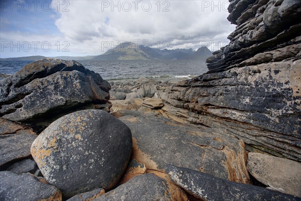 View from the rocky beach across the sea loch to the Cullin Mountains