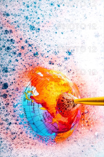 Paint dissolving through painting brush on the top of globe