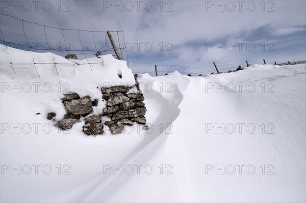 Wind-blown snowdrift on the back of a dry stone wall after a heavy snowstorm
