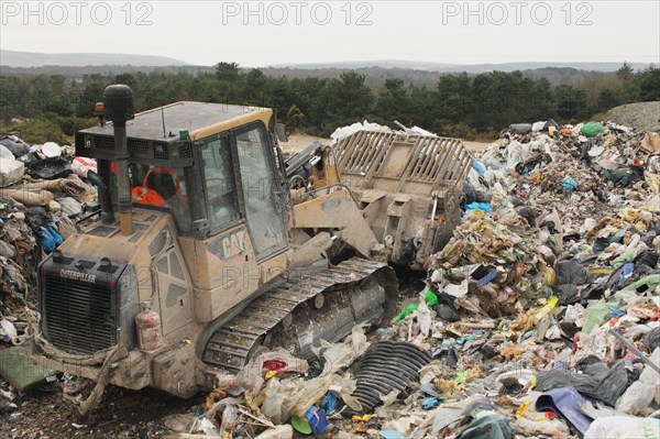 Bulldozer moving rubbish on landfill tip