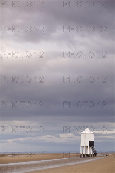Rain clouds and low wooden pole lighthouse on the beach at low tide
