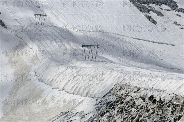 Textile protective covering to delay snow melt on ski slope with ski lift