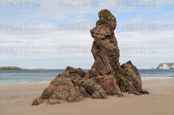 Outcrop of pink Lewisian gneiss rocks protruding from beach