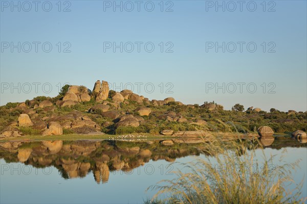 Reflection of rock formations with tufts of grass and lakescape in Los Barruecos