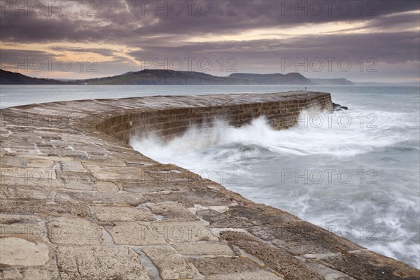 View of the harbour wall with the waves breaking at sunrise
