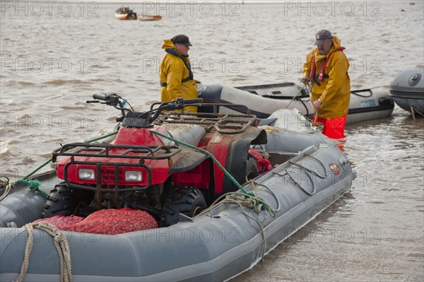 Licensed cockle pickers with quad bike in inflatable boat