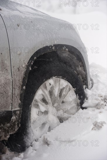 Close-up of a car wheel stuck in a snowdrift after a blizzard