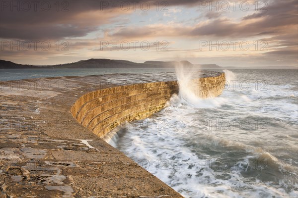 View of the harbour wall with the waves breaking at sunrise