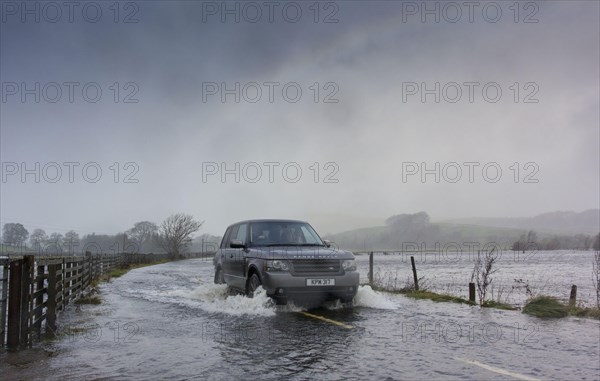 Range Rover driving on road flooded during heavy rain