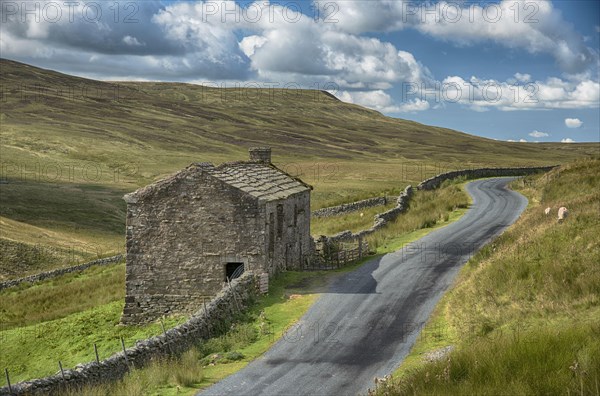View of dry stone walls and stone barn beside the road
