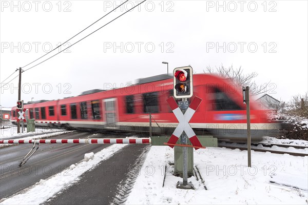 Passing train at a level crossing with barriers in sleet