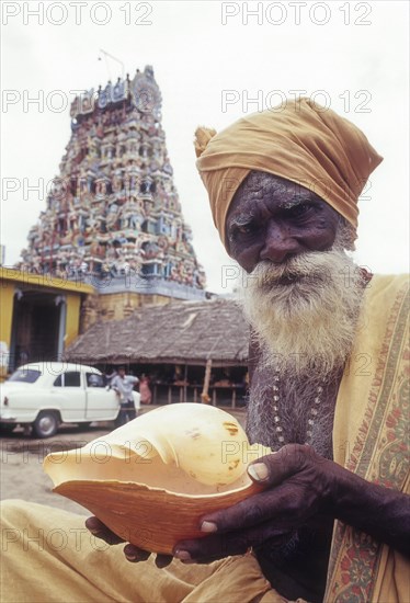 Sadhu holding conch standing infornt of Nataraja temple in Perur near Coimbatore