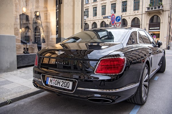 Parked luxury sedan Bentley Flying Spur First Edition in front of fashion shop Boutique Dior