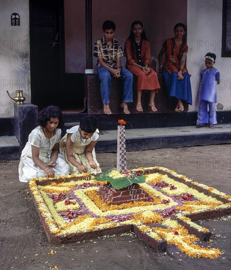 Girls doing floral decoration or pookalam during Onam festival in Kodungallur