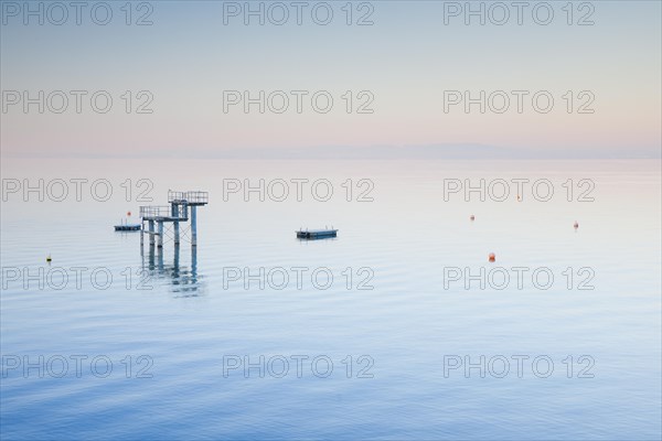 Morgenstimmung ueber dem Bodensee mit Blick zum Sprungturm und den Flossen der Freibadanlage Horn inmitten des Sees