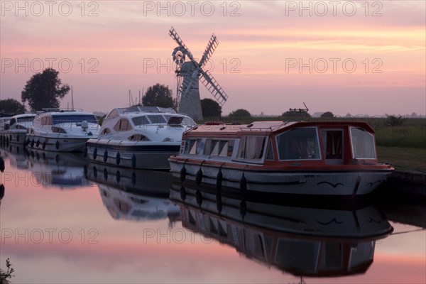 Pleasure boats moored near the wind pump at sunset