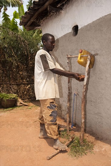 Man washes hands under self-made water tap from plastic container