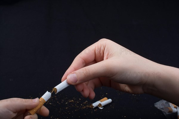 Hand is breaking a cigarette on a black background