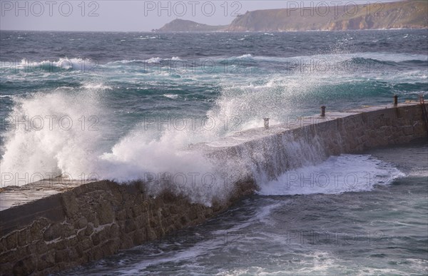 Waves breaking over the harbour wall