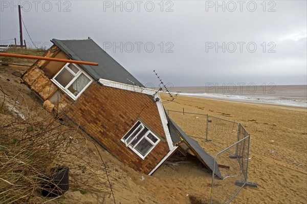 Eroded sea cliffs and damaged chalet after tidal surge in December 2013