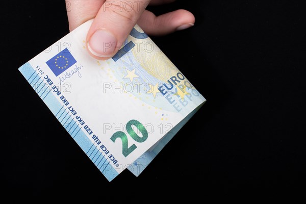 Hand holding 100 euro money cash isolated on black background