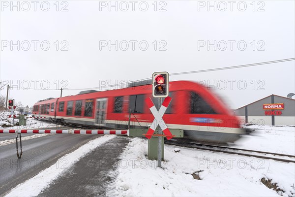 Passing train at a level crossing with barriers in sleet